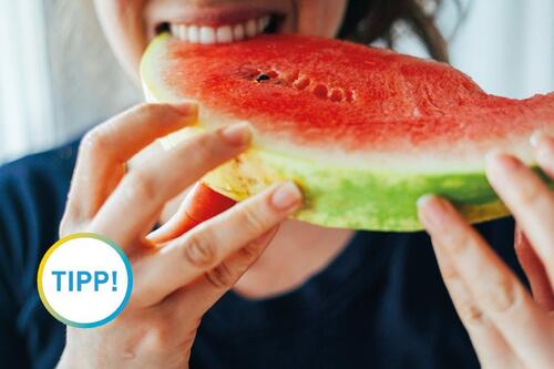 Frau beißt in ein Stück Melone Frau beißt in ein Stück Melone