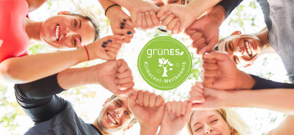 Mehrere Personen bilden einen Kreis aus Fäusten. In der Mitte ist ein Logo grünES-Klimacent-Wettbewerb zu sehen