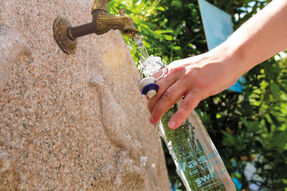 Ein Trinkwasserbrunnen an dem jemand eine Flasche auffüllt
